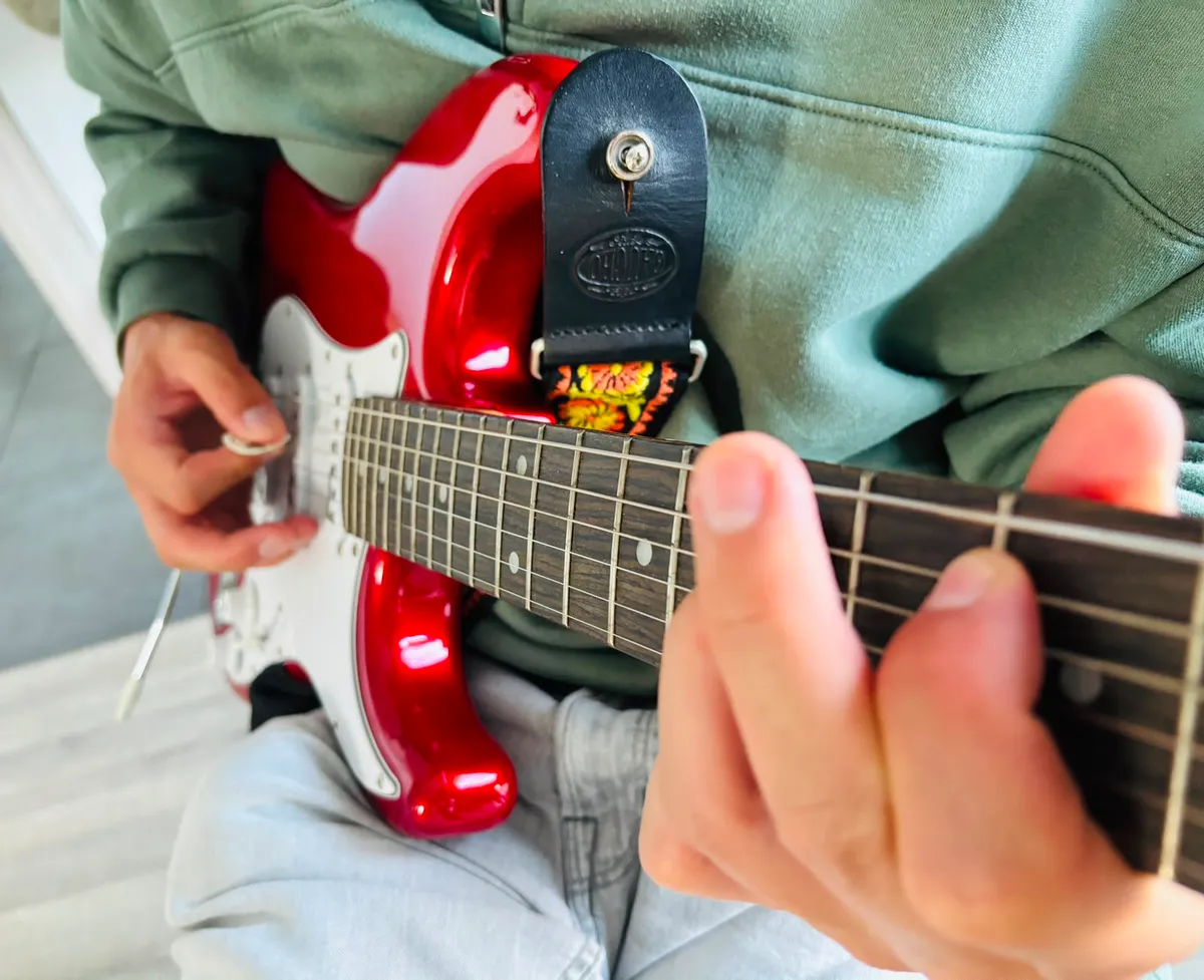 Speelhand op een rode elektrische gitaar, ideaal voor powerchords in Drop D