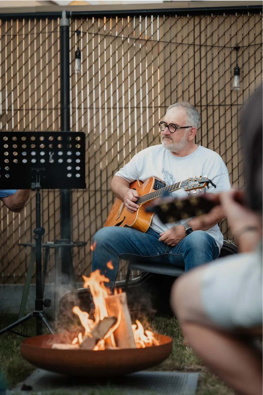 Gitarist speelt akoestische gitaar bij een knappend kampvuur