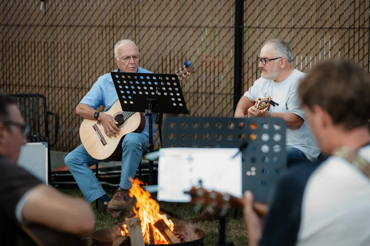 Gitaristen spelen samen rond het kampvuur tijdens een Summerjam-avond