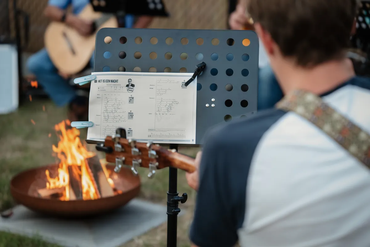 Liedjesblad op een standaard bij het kampvuur terwijl iemand gitaar speelt
