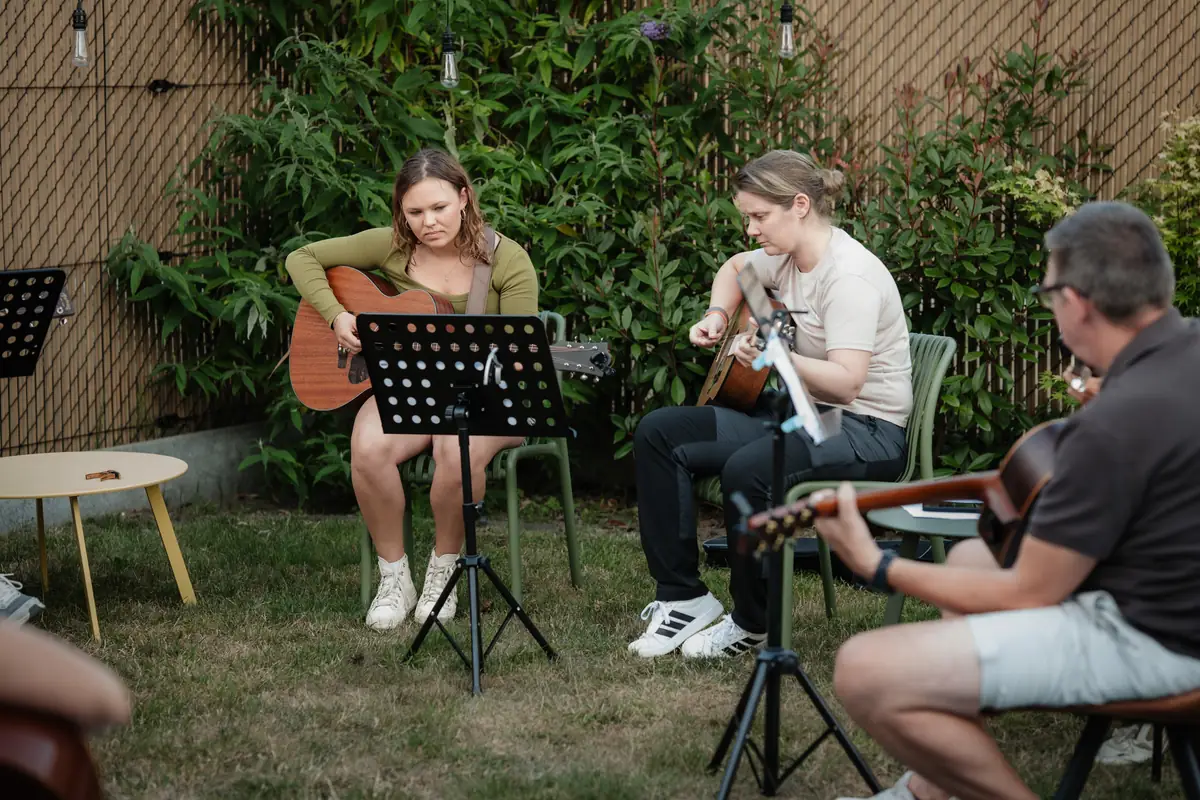Drie gitaristen spelen samen tijdens een kampvuuravond