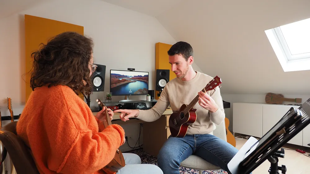 Dries toont een akkoord op de ukelele tijdens een les
