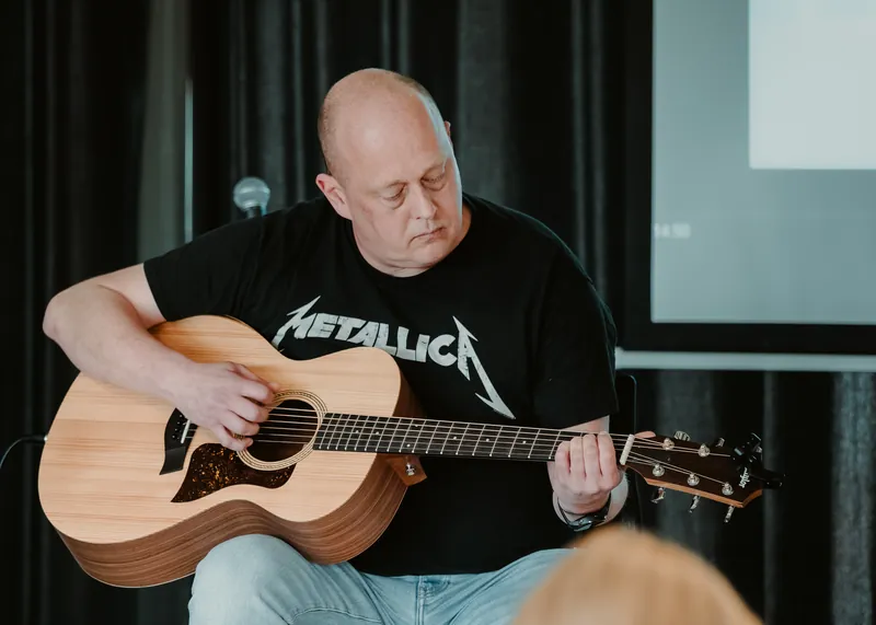 Volwassen leerling speelt gitaar tijdens de les